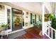 Inviting front porch with rocking chairs, hanging plants, and green-framed glass door at 1166 Nc Highway 87 N, Pittsboro, NC 27312
