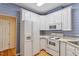 Cozy kitchen featuring white appliances, classic cabinets and blue patterned wallpaper at 1208 Copper Creek Dr, Durham, NC 27713