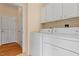 Bright laundry room with white washer and dryer, plus overhead cabinets at 1208 Copper Creek Dr, Durham, NC 27713