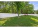 A verdant backyard featuring a pristine white privacy fence, towering mature trees, and a cozy seating area at 121 Talley Ridge Dr, Holly Springs, NC 27540