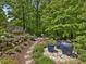 Lush backyard with a stone pathway, potted plants, and seating area, creating an inviting outdoor retreat at 123 Beech Forest Way, Pittsboro, NC 27312
