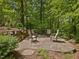 Charming backyard featuring a stone patio with comfortable seating, surrounded by lush greenery and mature trees at 123 Beech Forest Way, Pittsboro, NC 27312