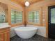 Bright bathroom featuring a modern soaking tub, hexagon tile floor, and wood paneled walls at 123 Beech Forest Way, Pittsboro, NC 27312