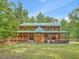 Log home with wraparound porch, stone steps, and grassy yard set amongst green trees at 123 Beech Forest Way, Pittsboro, NC 27312