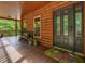 Welcoming front porch with seating, plants, log walls, and dark front door with butterfly doormat at 123 Beech Forest Way, Pittsboro, NC 27312