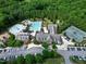 Bird's-eye view of a community clubhouse, pool, tennis courts, and parking amid a green landscape at 1241 Keith Rd, Wake Forest, NC 27587