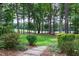Serene backyard with a stone pathway leading to the golf course and surrounded by mature trees and lush greenery at 1241 Keith Rd, Wake Forest, NC 27587