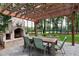 Cozy outdoor dining area features a brick fireplace under a wooden pergola with views of a golf course at 1241 Keith Rd, Wake Forest, NC 27587