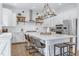 Bright kitchen features white cabinets, an island with seating, stainless steel appliances, and wooden shelves at 1241 Keith Rd, Wake Forest, NC 27587