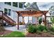 Charming patio featuring a wooden pergola, an outdoor fireplace, and a dining area surrounded by lush landscaping at 1241 Keith Rd, Wake Forest, NC 27587