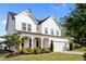 Bright home featuring a large two-car garage, a front porch with rocking chairs, and mature landscaping at 128 Highland Grove Way, Fuquay Varina, NC 27526