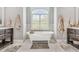 Bright bathroom featuring a freestanding tub under a window, marble floors, and dual vanities at 128 Paraggi Ct, Clayton, NC 27527
