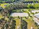 Aerial view of large equestrian arena with sand surface, surrounded by trees and pasture, with horse jumps and other farm buildings at 128 Paraggi Ct, Clayton, NC 27527