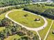 Aerial view of large equestrian course with sand surface, surrounded by grass and trees, with horse jumps and farm buildings at 128 Paraggi Ct, Clayton, NC 27527