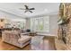 Cozy living room featuring a stone fireplace, plush sectional sofa, and bright natural light at 128 Paraggi Ct, Clayton, NC 27527