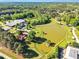 Aerial view of a large pond with surrounding trees and buildings, including a large equestrian complex and charming red-roofed house at 128 Paraggi Ct, Clayton, NC 27527