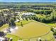 Aerial view of a large pond with surrounding trees and buildings, including a large equestrian complex at 128 Paraggi Ct, Clayton, NC 27527