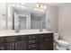 Dual sink bathroom with stained wood cabinets, framed mirrors, and modern light fixtures at 1314 Catch Fly Ln, Durham, NC 27713