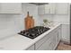 Close up of kitchen stove cooktop with cabinets and tiled backsplash at 1513 Armscroft Lane, Apex, NC 27502