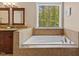 Well lit bathroom with bathtub, tile surround, and window with wooded view at 1605 Sassafras St, Durham, NC 27712