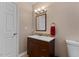 Bathroom with dark wood vanity, decorative mirror, and neutral wall and floor tiles at 1605 Sassafras St, Durham, NC 27712