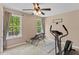 Bedroom with ceiling fan, two windows with wooded views, and exercise equipment at 1605 Sassafras St, Durham, NC 27712
