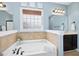 Bathroom showcases a luxurious soaking tub with tile surround, framed windows, and stylish fixtures at 187 Old Johnson Rd, Wendell, NC 27591
