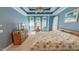 Spacious primary bedroom featuring tray ceilings, windows, and dresser with a view of the bed at 19 Rivers Edge Ct, Timberlake, NC 27583