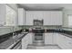 Bright kitchen featuring stainless steel appliances, granite countertops, and sleek white cabinets at 20 Keswick Ct, Durham, NC 27713