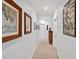 Long hallway with neutral walls displaying framed artwork and a cabinet, offering a gallery-like ambiance at 20011 Bragg, Chapel Hill, NC 27517
