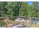 This is a close up of the outdoor deck with wood railings and table with a drink cooler against a natural treed backdrop at 2049 Rainy Lake St, Wake Forest, NC 27587