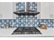Close-up of a kitchen featuring blue backsplash, stainless steel vent hood and gas cooktop at 2049 Rainy Lake St, Wake Forest, NC 27587