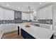 Charming kitchen featuring an island, white cabinetry, stainless appliances, and a light-blue backsplash at 2049 Rainy Lake St, Wake Forest, NC 27587