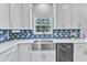 Close-up of a kitchen sink with white cabinets, stainless steel appliances, and blue backsplash at 2049 Rainy Lake St, Wake Forest, NC 27587