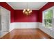 Elegant dining room featuring bold red walls, wainscoting, and hardwood floors at 210 Mediate Dr, Raleigh, NC 27603