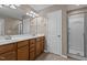 Bright bathroom with double vanities, framed mirror, and glass enclosed shower, providing a spa-like experience at 221 Hammond Wood Pl, Morrisville, NC 27560