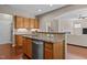 Open kitchen view with a granite island, stainless steel appliances, wooden cabinets, and hardwood flooring at 221 Hammond Wood Pl, Morrisville, NC 27560