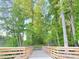 Scenic view of a wooden bridge leading to a nature trail surrounded by lush trees at 222 Oak Branch Trl, Garner, NC 27529