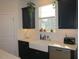 Well-lit kitchen featuring black cabinets, a farmhouse sink, and stainless steel appliances near a bright window at 222 Oak Branch Trl, Garner, NC 27529