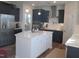 Well-lit kitchen with black cabinetry, stainless steel appliances, quartz countertops, and a spacious island with white cabinets at 222 Oak Branch Trl, Garner, NC 27529
