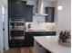 Bright kitchen features dark cabinets, stainless steel appliances, white herringbone backsplash, and quartz countertop island at 222 Oak Branch Trl, Garner, NC 27529