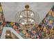 Unique gold chandelier fixture hangs from the ceiling with bright tropical floral wallpaper at 2306 Byrd St, Raleigh, NC 27608