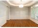 An empty dining room features hardwood floors, a tray ceiling, and large windows at 2405 Flints Pond Cir, Apex, NC 27523