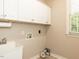 Functional laundry room with white cabinetry, utility sink, and window for natural light at 2405 Flints Pond Cir, Apex, NC 27523