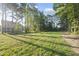 A wide open and grassy backyard is framed by trees at 300 Scotland Dr, Youngsville, NC 27596