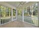 A screened porch with wooden floors and white railings offers views of the wooded backyard at 300 Scotland Dr, Youngsville, NC 27596