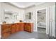 Spacious bathroom with wood cabinets, double sinks, vanity mirrors, and a glass-enclosed shower at 30150 Walser, Chapel Hill, NC 27517