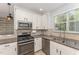 Bright kitchen with white cabinets, stainless steel appliances, and a large window offering natural light at 302 Red Elm Dr, Durham, NC 27713