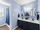 Bathroom featuring double sink vanity with framed mirrors, modern lighting, and a shower/tub combo at 3204 Terrel Mill Rd, Raleigh, NC 27616