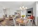 Open-concept dining room boasts a chandelier over a wooden table and leads to a living area with fireplace and TV at 321 Everly Mist Way, Wake Forest, NC 27587